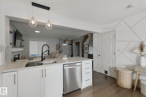 Kitchen island featuring a single-basin sink, black gooseneck faucet, and stainless steel dishwasher - 8535 Ellis Link Link Nw, Edmonton, AB 