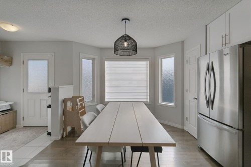 Recessed lighting, wood-finish flooring, white paneled door, stainless steel refrigerator, and white upper cabinetry - 8535 Ellis Link Link Nw, Edmonton, AB 