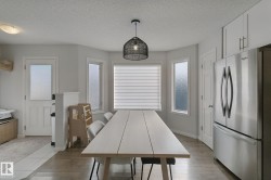 Recessed lighting, wood-finish flooring, white paneled door, stainless steel refrigerator, and white upper cabinetry - 