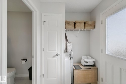 Entryway with a solid panel door, frosted glass exterior door, wire shelving, and a built-in wood-finish cabinet - 8535 Ellis Link Link Nw, Edmonton, AB 