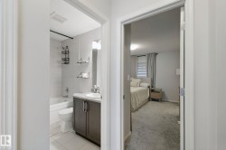 Bathroom with a bathtub, white tile surround, and a dark wood-finish vanity with an integrated sink - 