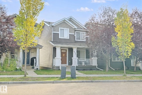 Two-story residence featuring a covered front porch with white railing, horizontal siding, and prominent front-facing windows - 8535 Ellis Link Link Nw, Edmonton, AB 