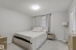Textured ceiling, wall-mounted light fixture, light gray walls, window with blinds and drapes, and light gray carpeting - 