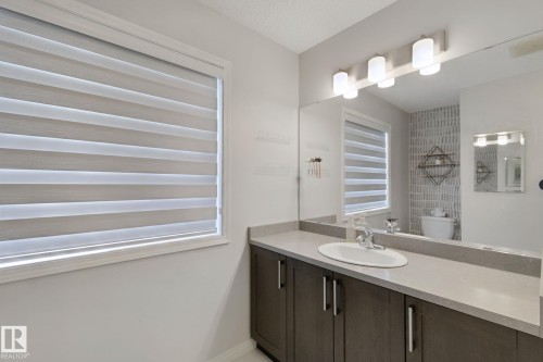 Vanity with integrated sink, stone countertop, and wood-finish cabinetry - 8535 Ellis Link Link Nw, Edmonton, AB 
