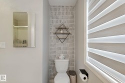 White toilet with a patterned accent wall, geometric wall-mounted shelving, and a horizontal striped window blind - 