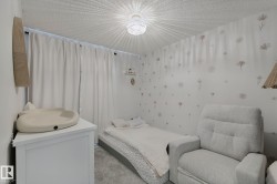 Textured ceiling with a woven pendant light fixture, soft white drapery, and neutral wall decor - 