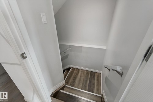 Staircase with wood-finish flooring, white risers, and wall-mounted handrails - 8535 Ellis Link Link Nw, Edmonton, AB 