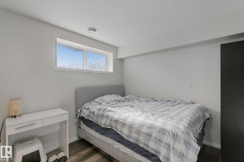 Wood-finish flooring with light gray walls, featuring a high transom window and a dark panel door - 8535 Ellis Link Link Nw, Edmonton, AB 