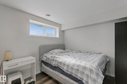 Wood-finish flooring with light gray walls, featuring a high transom window and a dark panel door - 