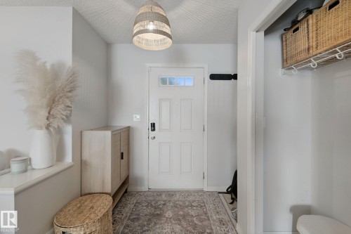 Entryway featuring a decorative pendant light, paneled door with glass inserts, and built-in shelving with storage baskets - 8535 Ellis Link Link Nw, Edmonton, AB 