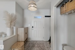 Entryway featuring a decorative pendant light, paneled door with glass inserts, and built-in shelving with storage baskets - 