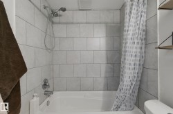 Bathtub with light gray subway tile surround and chrome fixtures - 