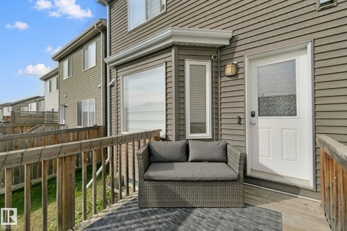 Private deck with wooden railings, vinyl siding exterior, and a white entry door with frosted glass - 8535 Ellis Link Link Nw, Edmonton, AB 