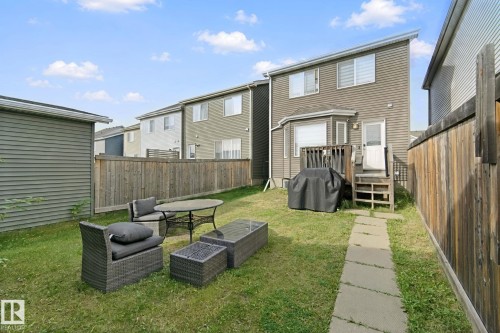 Rear exterior with wood-finish siding, a ground-level deck, bay window, and privacy fencing - 8535 Ellis Link Link Nw, Edmonton, AB 