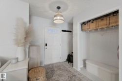 Foyer featuring a textured pendant light fixture, white paneled entry door, and a built-in closet with shelving - 