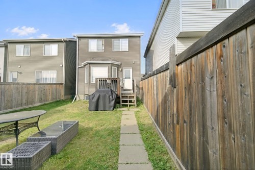 Expansive fenced backyard with a concrete paver walkway, leading to a wooden deck - 8535 Ellis Link Link Nw, Edmonton, AB 