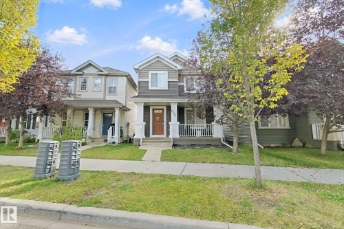 Two-story home with a covered front porch featuring white railings and columns - 8535 Ellis Link Link Nw, Edmonton, AB 