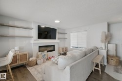 Recessed lighting, wood-finish flooring, a wall-mounted fireplace, and open shelving - 