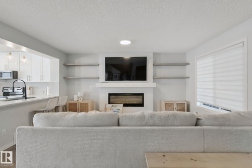 Living area featuring a built-in electric fireplace, white mantel, and integrated shelving - 8535 Ellis Link Link Nw, Edmonton, AB 