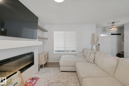Built-in fireplace, floating shelves, recessed lighting, wood-finish flooring, and a decorative light fixture - 8535 Ellis Link Link Nw, Edmonton, AB 