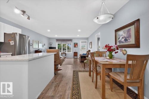 Open-concept living space with wood-finish flooring, recessed lighting, and a kitchen island featuring a light-colored countertop - #125 4610 50 Ave, Stony Plain, AB 