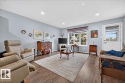 Recessed lighting, wood-finish flooring, light blue wall paint, a white door with a glass panel, and a multi-pane window - 