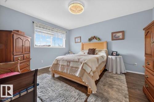 Spacious room featuring wood-finish flooring and a central ceiling light fixture - #125 4610 50 Ave, Stony Plain, AB 