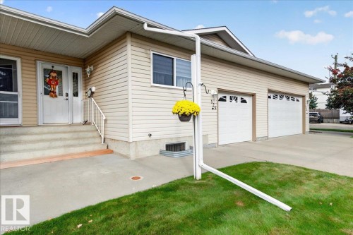 Two-car garage with individual doors, concrete driveway, concrete front porch, and exterior siding - #125 4610 50 Ave, Stony Plain, AB 