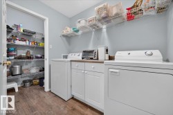 Laundry area featuring wood-finish flooring, white cabinetry, and a countertop workspace - 