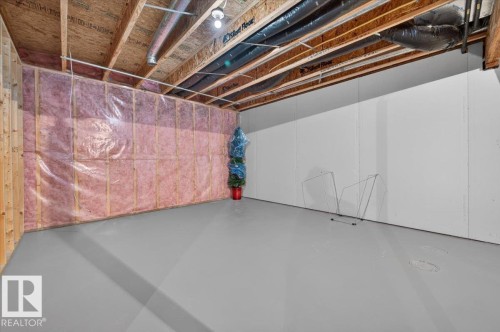 Unfinished basement with exposed wood framing, insulation, and partially finished white paneling - #125 4610 50 Ave, Stony Plain, AB 