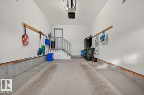 Spacious garage with concrete flooring, painted walls, and a built-in staircase - #125 4610 50 Ave, Stony Plain, AB 
