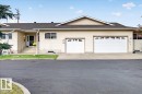 Siding exterior with multiple windows, two-car garage, and concrete entry steps - #125 4610 50 Ave, Stony Plain, AB 