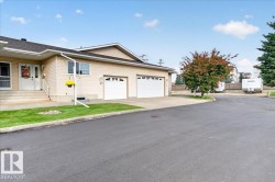 Two-car attached garage, paved driveway, mature trees, manicured lawn, and exterior siding - 