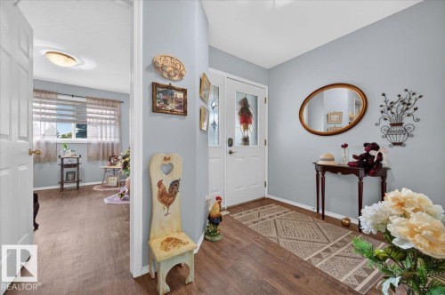 Light gray wall paint, wood-finish flooring, white interior doors, and a front entry door with decorative glass inserts - #125 4610 50 Ave, Stony Plain, AB 