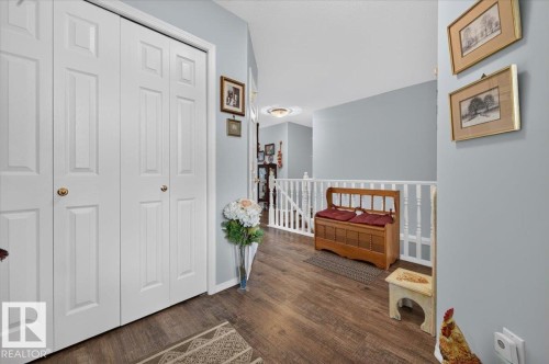 Wood-finish flooring throughout, featuring a white spindle railing and light blue wall tones - #125 4610 50 Ave, Stony Plain, AB 