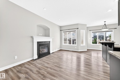 Recessed lighting, wood-finish flooring, white trim, gas fireplace with white mantel, and ample windows - Edmonton, AB 