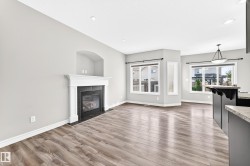 Recessed lighting, wood-finish flooring, white trim, gas fireplace with white mantel, and ample windows - 