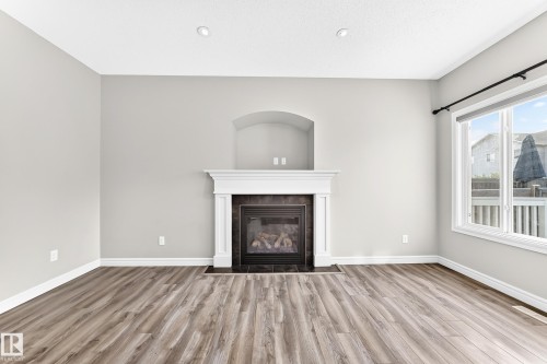 Recessed lighting, wood-finish flooring, built-in fireplace with mantel, tiled fireplace surround, and large window - Edmonton, AB 