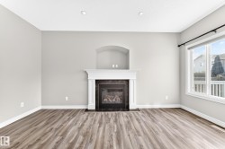 Recessed lighting, wood-finish flooring, built-in fireplace with mantel, tiled fireplace surround, and large window - 