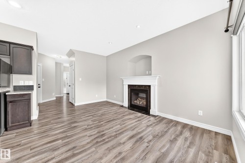 Living area with wood-finish flooring, a white mantel fireplace, and a light gray wall finish - Edmonton, AB 