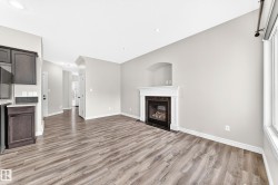 Living area with wood-finish flooring, a white mantel fireplace, and a light gray wall finish - 