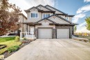 Two-story residence featuring light gray siding with dark trim accents and stone facade elements - Edmonton, AB 