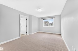 Neutral color palette with light gray walls, carpet flooring, a single window, and a white interior door with black hardware - 
