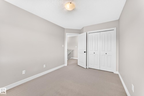 Plush carpet flooring, neutral painted walls, white trim, bi-fold closet doors, and an overhead flush-mount light fixture - Edmonton, AB 