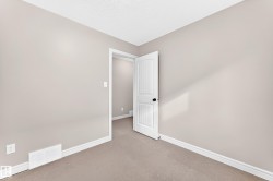 Soft neutral wall paint and carpeting, white trim, and a white paneled interior door with a black knob - 