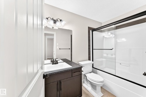 Bathroom with a dark wood-finish vanity, white rectangular sink, and a dark countertop - Edmonton, AB 