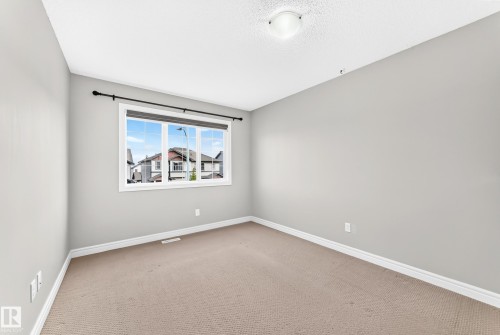 Neutral wall color, window with exterior scenery, overhead flush mount light fixture, and carpeted flooring - Edmonton, AB 