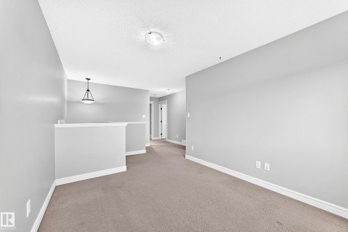 Neutral-toned carpeting, light gray painted walls, a flush-mount ceiling light, and a hanging pendant light fixture - Edmonton, AB 