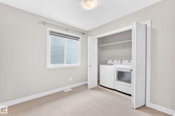 Integrated laundry closet with bi-fold doors, white washer and dryer, and built-in shelving - 