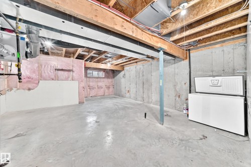 Unfinished basement featuring concrete flooring, exposed wood joists, structural support beam, and small window - Edmonton, AB 